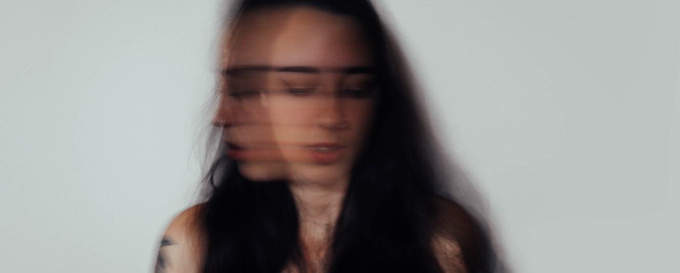 double exosed photo of a woman. looking forward and to the side, slightly dowcast. The image is meant to highlight anxiety.