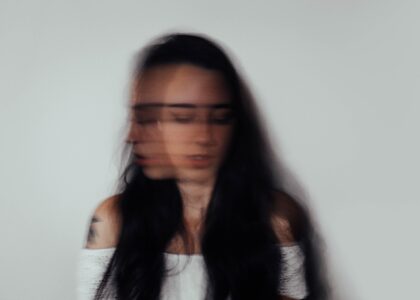 double exosed photo of a woman. looking forward and to the side, slightly dowcast. The image is meant to highlight anxiety.